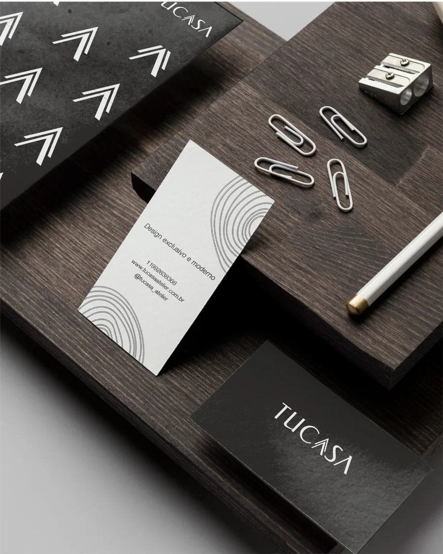 Papelaria da TuCasa sobre mesa de madeira escura: cartões, envelopes e clipes.